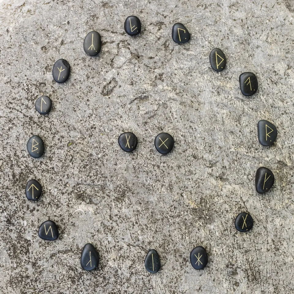 Une ronde de runes sur galets noirs posée sur le sable
